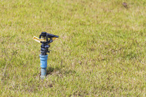 An above-ground water sprinkler in a grass yard
